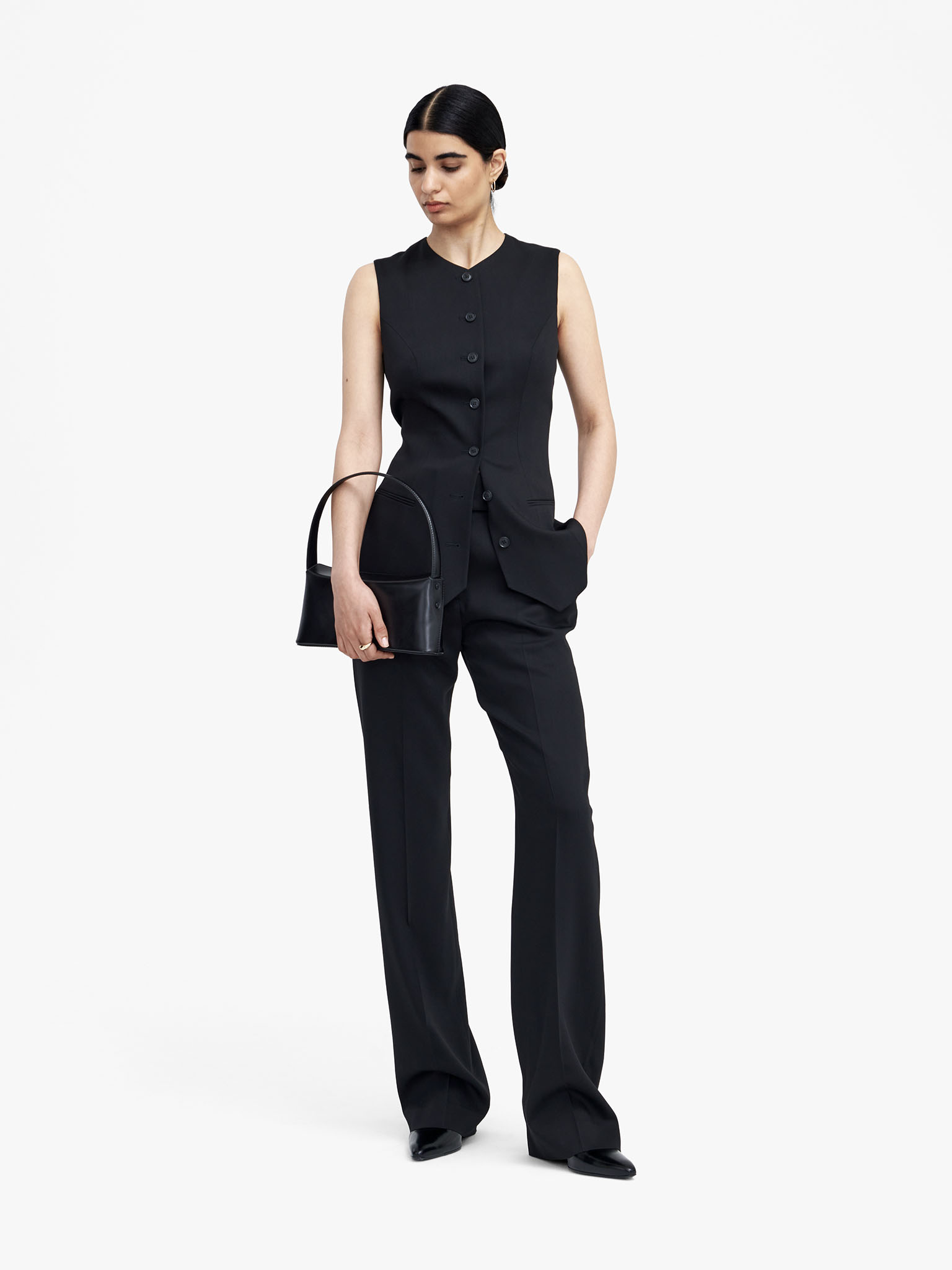 Woman in black suit with waistcoat and black bag
