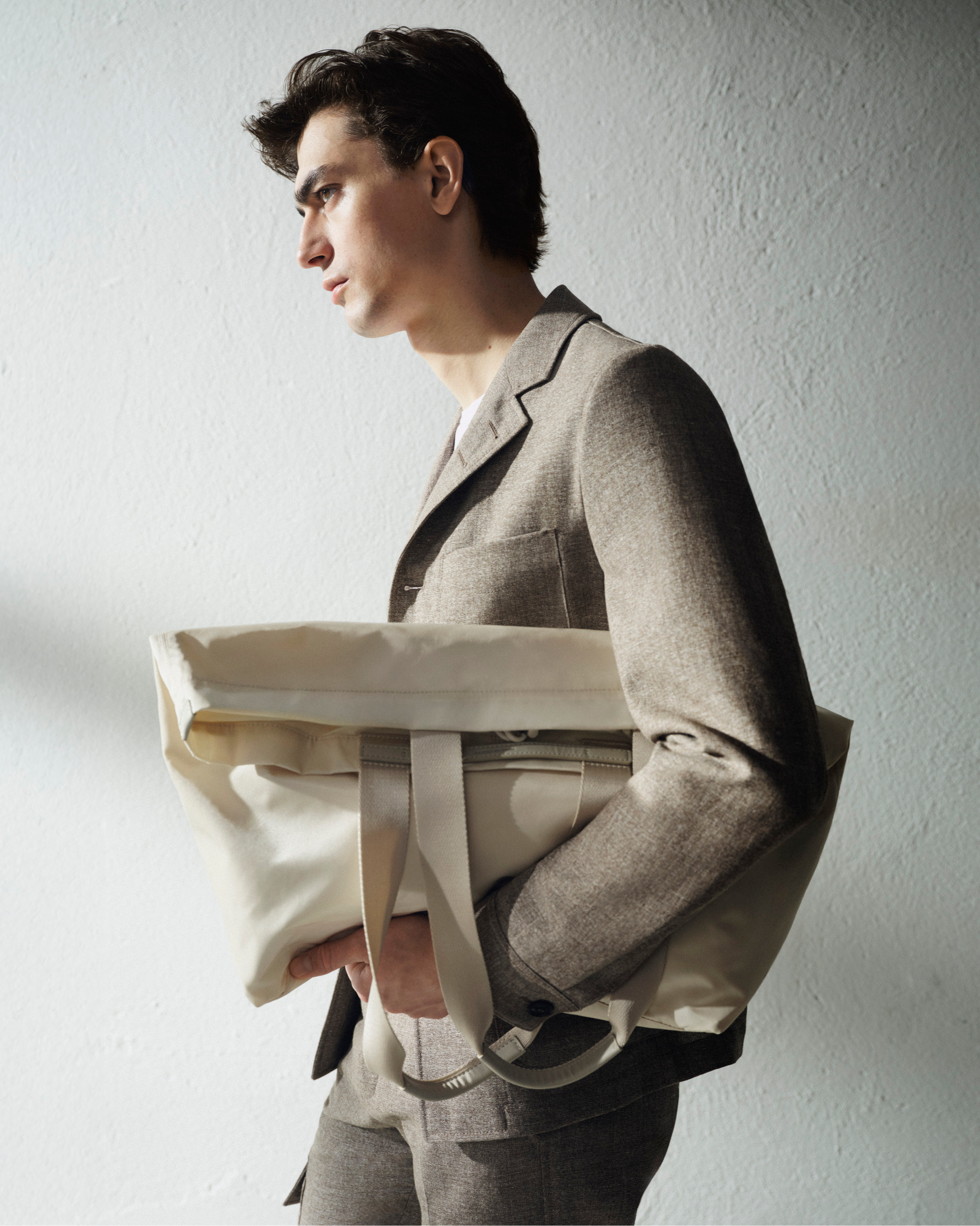 man in beige blazer and creme bag