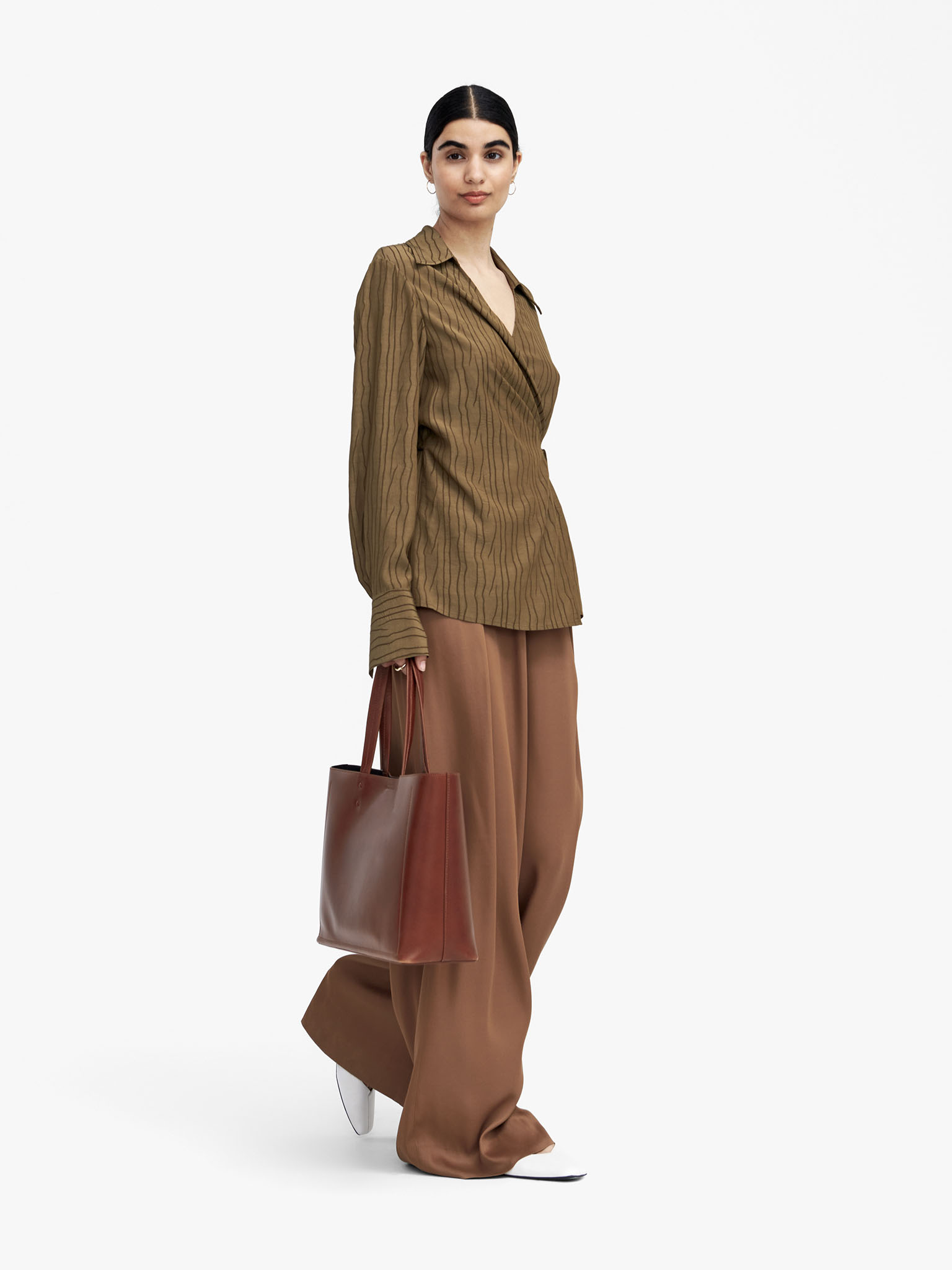 Woman in relaxed brown trousers and relaxed shirt
